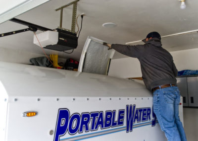 photo of man opening top hatch on water trailer